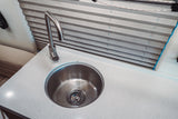RV rental interior showing a clean kitchen sink, modern faucet, and white speckled countertop with privacy blinds.
