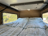 Cozy RV rental interior with a comfortable bed and scenic views from the side windows.