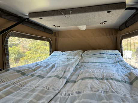 Cozy RV rental interior with a comfortable bed and scenic views from the side windows.