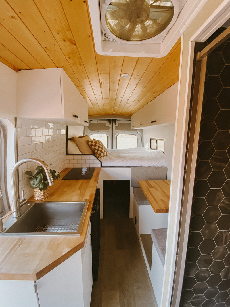 Explore this modern RV rental interior! Features a compact kitchen, cozy bed, and dining nook, ideal for travel. — photo 3