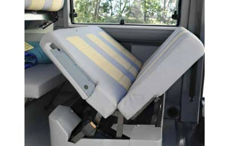 RV rental camper van's convertible bed/seat. Striped cushions are partially folded, revealing adaptable interior space.