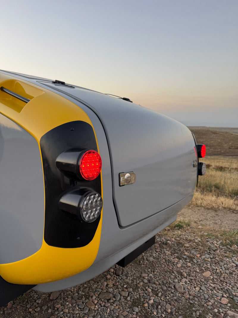 Close-up: rear of a gray and yellow teardrop RV rental with bright LED rear lights. Perfect for your next road trip! — photo 4