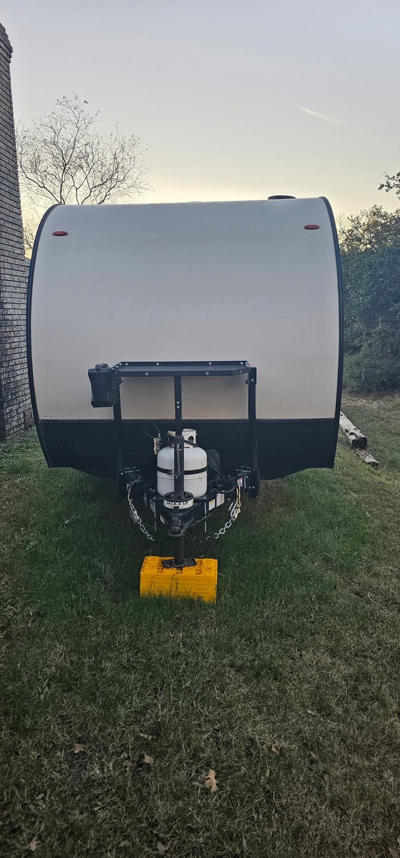  parked on grass at dusk.|Rear view of a white Texas travel trailer (RV rental) parked on green grass — photo 3