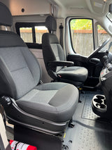 Clean RV rental cabin with swivel front seats, steering wheel, and floor mats. Note the fire extinguisher.