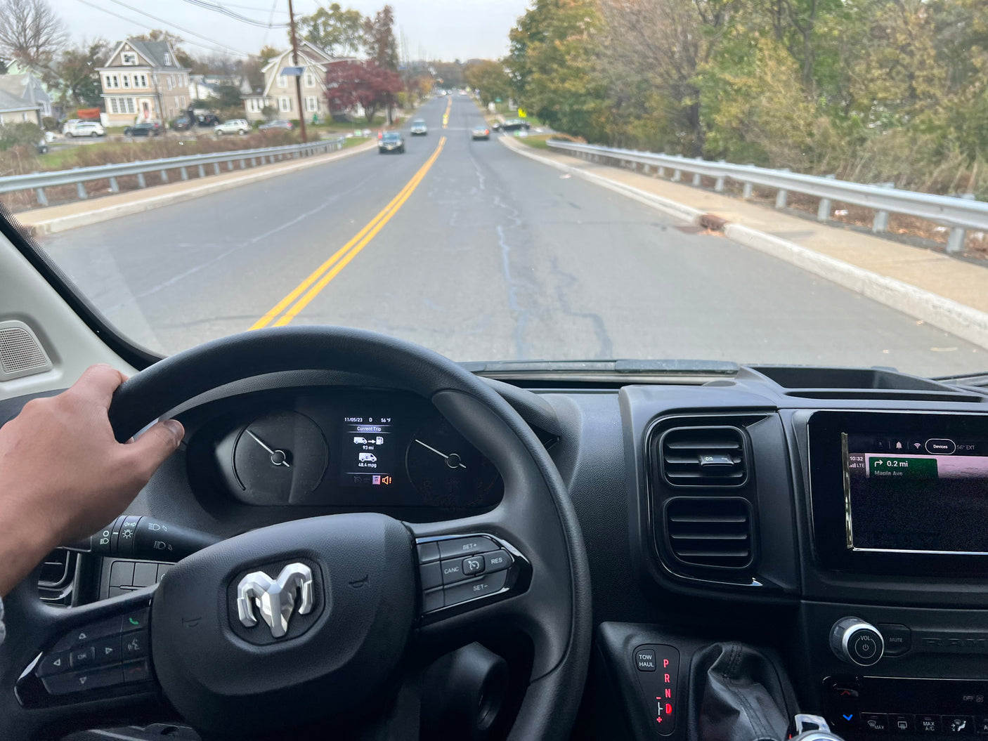 Driver's view from an RV rental, navigating a road with homes. Dashboard shows 56°F, 93 miles, and GPS to Maple Ave.