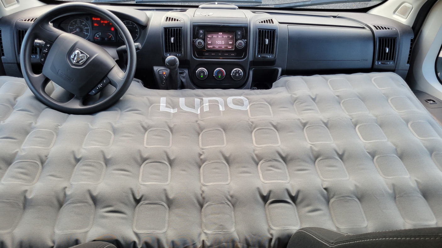 This rv rental interior features a Luno inflatable mattress set up for sleeping, converting the front cabin into a cozy bed.