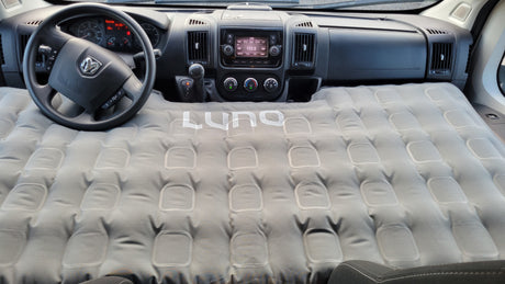 This rv rental interior features a Luno inflatable mattress set up for sleeping, converting the front cabin into a cozy bed.