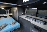 Explore this RV rental's modern campervan interior, featuring a cozy bed, sleek kitchen area, and scenic window.