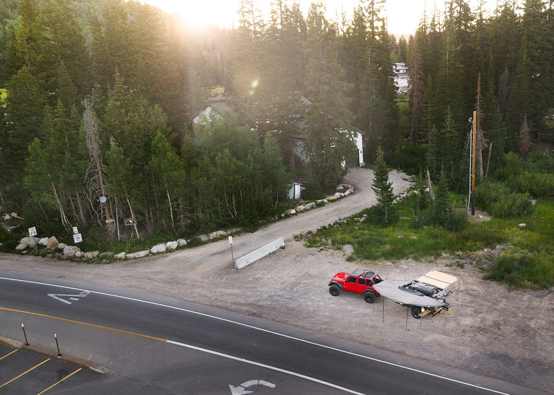 Red Jeep & compact camping trailer with deployed awnings by a scenic road in a forest. A unique RV rental for wilderness trips. — photo 4