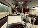 RV rental interior: Four people relaxing and working on a laptop in a cozy mobile office.