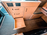 Inside an RV rental: light wood cabinetry with USB/AC outlets, storage drawers, and a bench seat for comfortable travel.