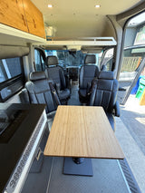 Explore in comfort: a detailed view of an RV rental's spacious interior with kitchen, table, and four swivel seats.