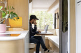 Man works on laptop in a stylish RV rental, featuring light wood interior and nature views. Ideal for remote work.