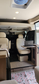 Step inside this modern RV rental with swiveling cream seats, a laptop workstation, and light wood flooring for your next adventure.