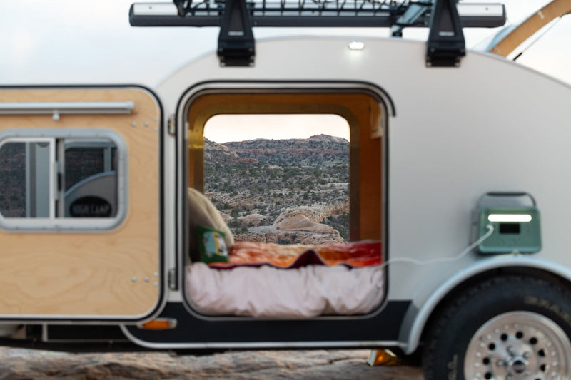  charging device on fender. Pickup truck in outdoor setting.|RV rental comfort: A teardrop trailer's open door reveals a cozy bed & stunning desert vista — photo 9