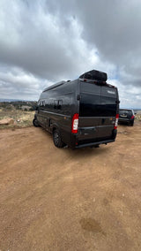 Dark grey Winnebago Solis RV rental on a dirt road, ready for camper van travel under overcast skies.