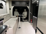 Luxury rv rental interior with plush seating, adjustable tables, front cabin view, and a fire extinguisher for safety.