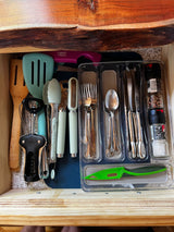 RV rental kitchen drawer neatly packed with common utensils: spatulas, corkscrew, tongs, flatware, and spices.