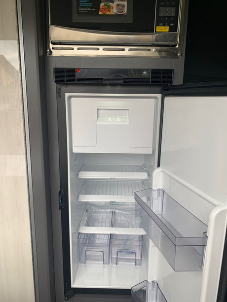 Essential RV rental appliances: an open Norcold refrigerator and microwave, ready for your road trip meals.