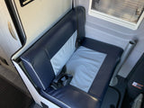 Step inside this RV rental: a cozy passenger bench seat with seatbelts, blue & gray upholstery, and a window for scenic views.