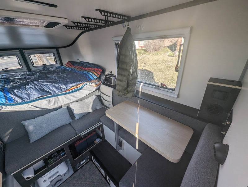 Cozy RV rental interior with a bed, dinette, and ample built-in storage for travel. — photo 5