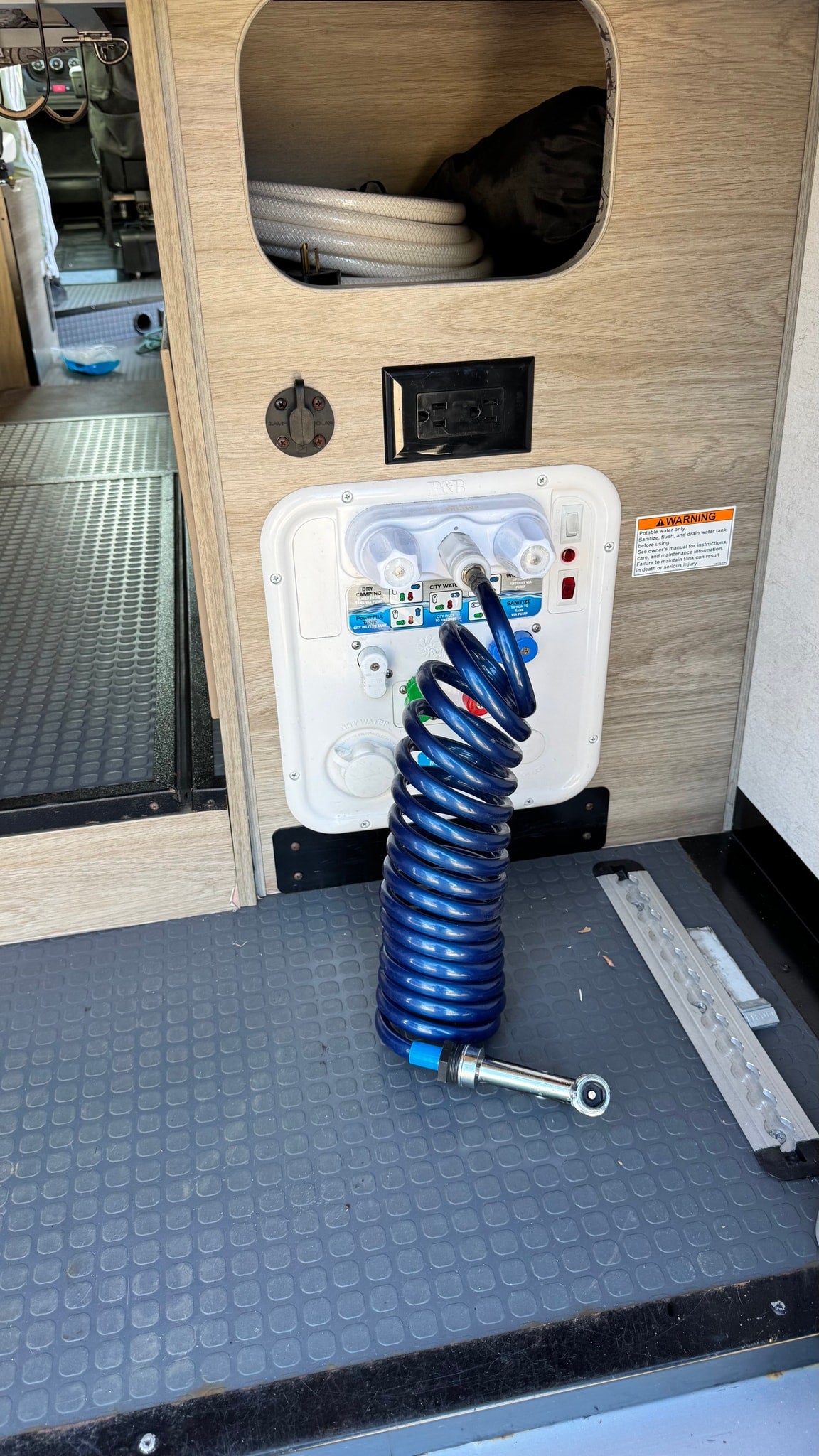  a comfy bed faces a large window overlooking a green campsite with tents and trees outside.|Inside an RV rental — photo 14
