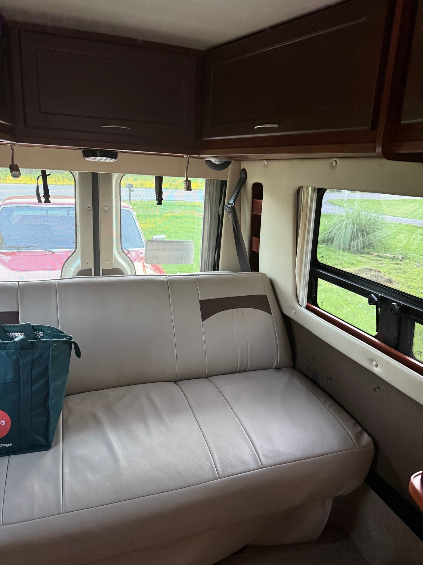 Spacious RV rental interior with light leatherette seating, dark wood cabinets, and scenic window views.