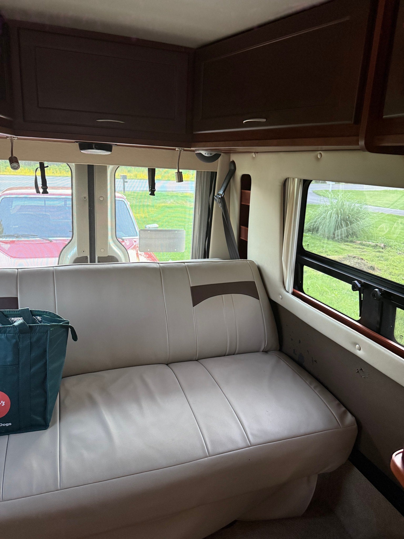 Spacious RV rental interior with light leatherette seating, dark wood cabinets, and scenic window views.
