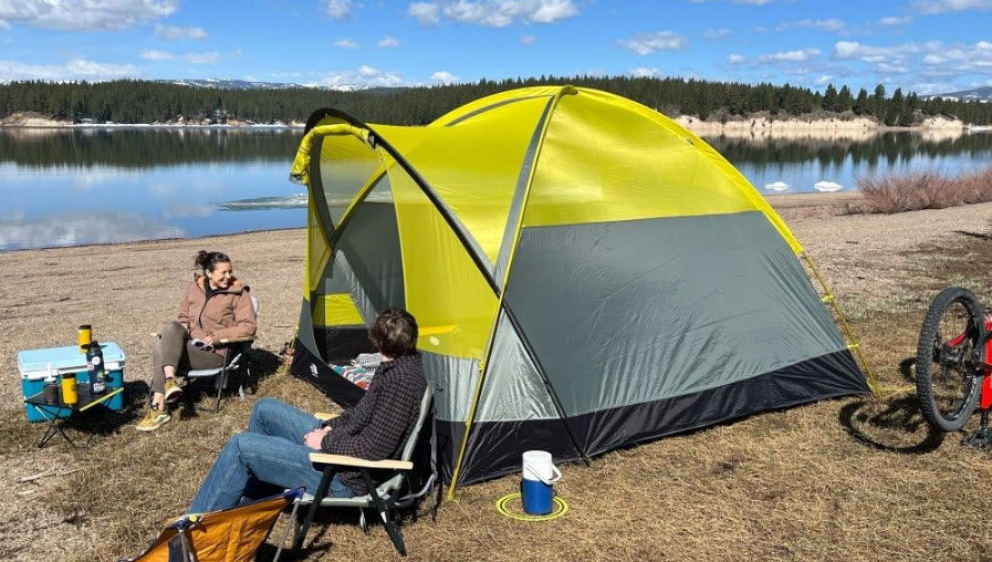 Enjoying lakeside camping! This RV rental alternative offers a cozy tent, chairs, and stunning views for outdoor recreation by the lake.