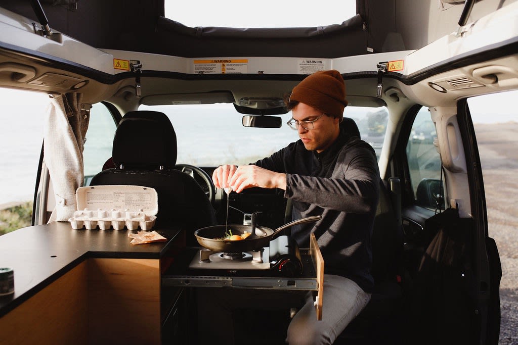  depicting adventure and motion.|Rv rental adventure: Man cooking breakfast inside a camper van — photo 3