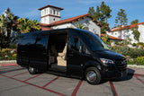 Luxury black Mercedes Sprinter van, an upscale RV rental, parked amidst elegant Spanish architecture and lush gardens.