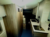 RV rental interior: A bright, modern camper van galley kitchen with a sink, cabinets, and narrow hallway. Perfect for travel.