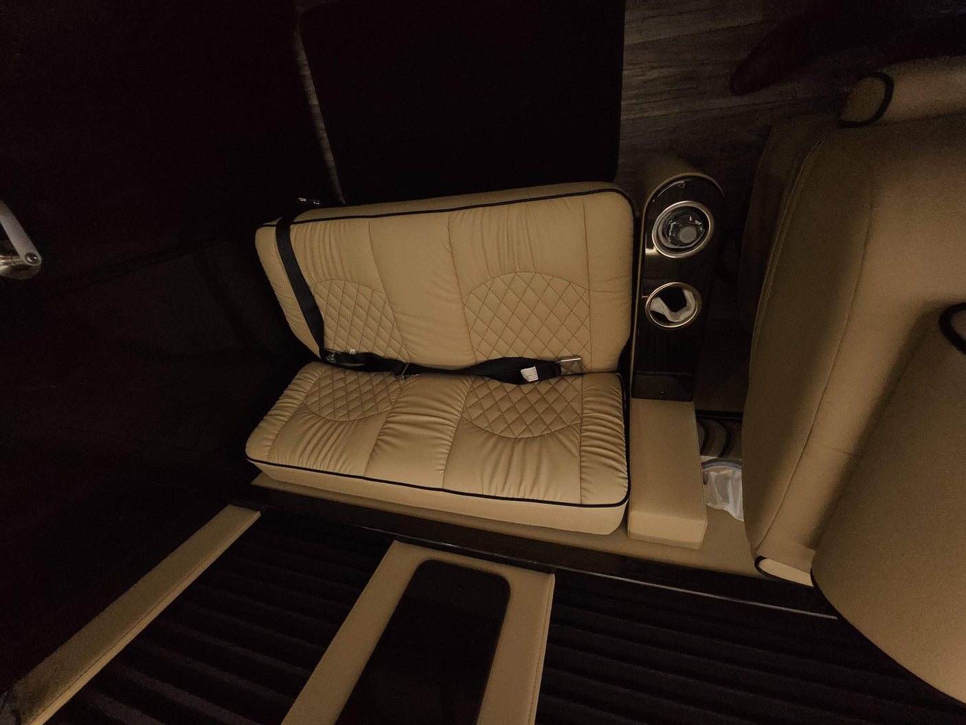 Plush, quilted beige bench seat & illuminated cup holders in a luxury RV rental interior.