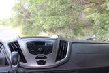 Inside an **rv rental**: dashboard with audio system controls, gear shift, and air vents, overlooking a road and trees.