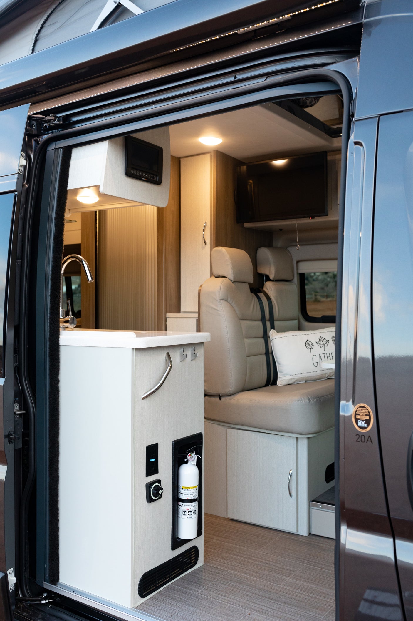 Step inside this modern rv rental, featuring a compact kitchen, comfortable seating, and a TV for your adventures.