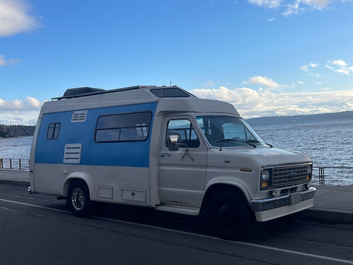 Vintage blue and white RV rental parked by the scenic ocean with blue skies and clouds, ready for your next adventure. — photo 14