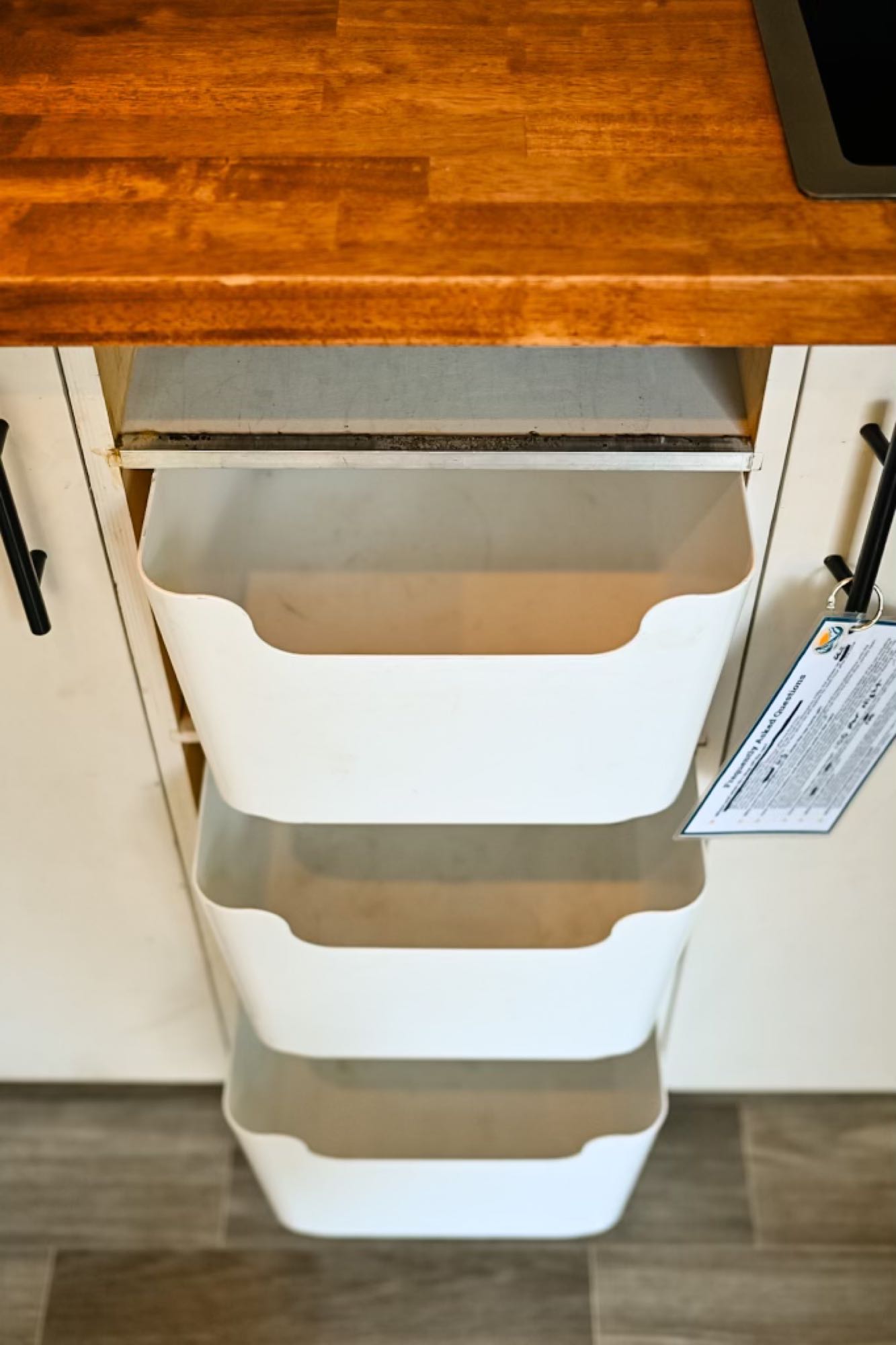 RV rental storage solutions: Three white pull-out bins under a wooden counter for organized living.