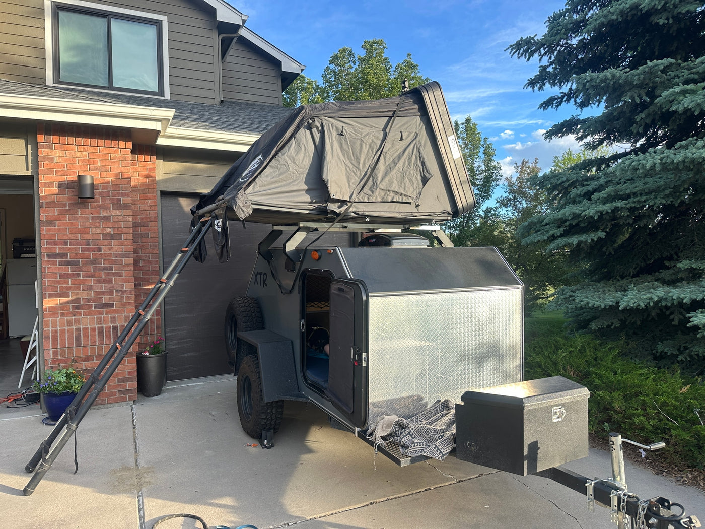 XTR off-road trailer with an open rooftop tent & ladder, parked on a driveway. A unique option for an RV rental camping adventure. — photo 2