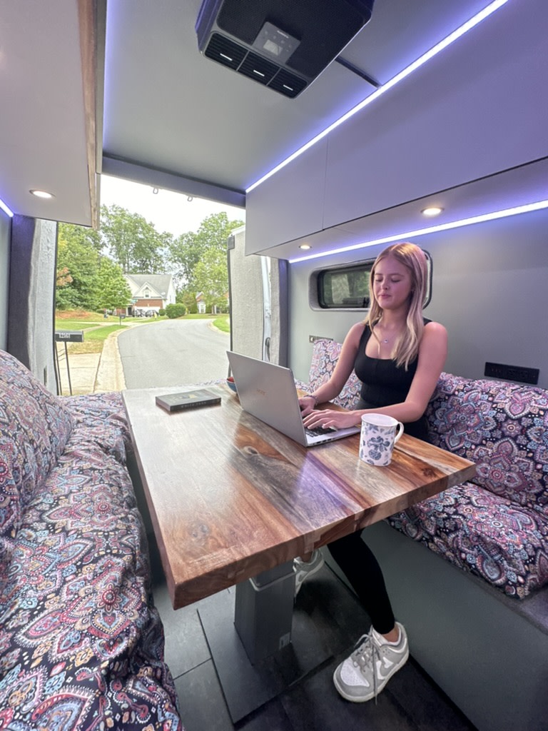  featuring a woman and her cat enjoying the comfortable interior with an extendable outdoor table.|Prepare meals in this well-equipped rv rental campervan kitchen — photo 6