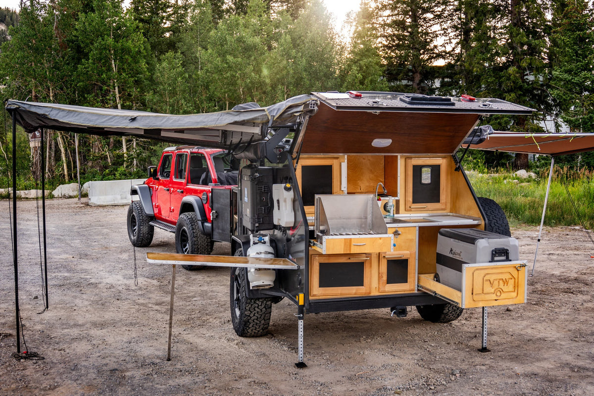 This RV rental setup, featuring a red Jeep and an off-road teardrop camper with a fully equipped outdoor kitchen, is ready for overlanding. — photo 11