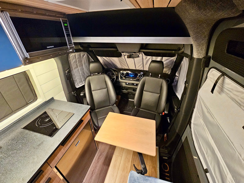Experience a cozy RV rental interior: microwave, induction cooktop kitchen, fold-out table, & front cabin with privacy shades. — photo 9