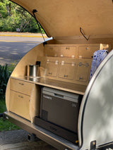 This RV rental teardrop camper reveals its open rear galley kitchen, featuring a Dometic cooler, drawers, and ample storage cabinets.