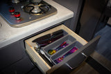 RV rental kitchen featuring an open drawer with vibrant iridescent cutlery and knives next to a compact two-burner stove.