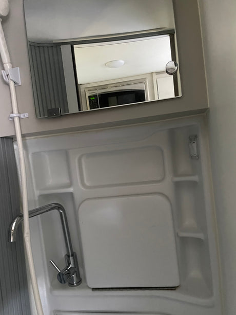 RV rental: A compact wet bath with sink, shower, and a mirror reflecting the microwave in the living area.