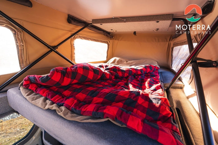  ready for adventure.|Experience cozy comfort in this RV rental! A spacious camper van sleeping area features a comfy bed with a warm red plaid blanket