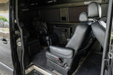 Inside a luxurious RV rental van with black leather seating, entertainment controls, and privacy blinds.