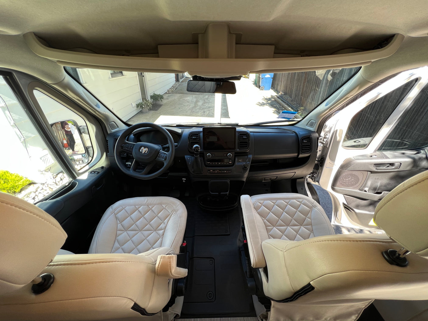 Spacious rv rental van cockpit, featuring light-colored quilted seats and a modern digital dashboard.