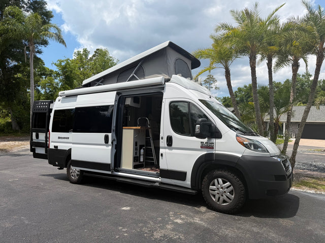White pop-top camper van rv rental with open side door revealing interior kitchen