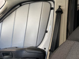 RV rental window with custom-fit reflective insulation/sunshade, showing the seatbelt, door handle, and airbag label.