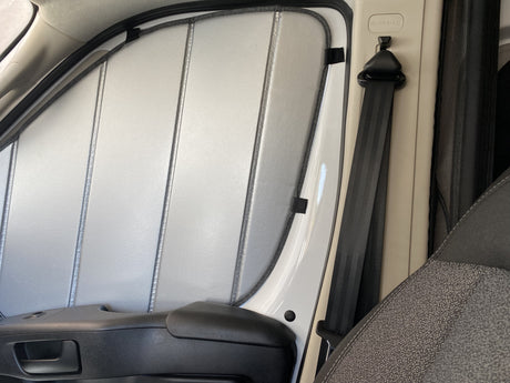 RV rental window with custom-fit reflective insulation/sunshade, showing the seatbelt, door handle, and airbag label.